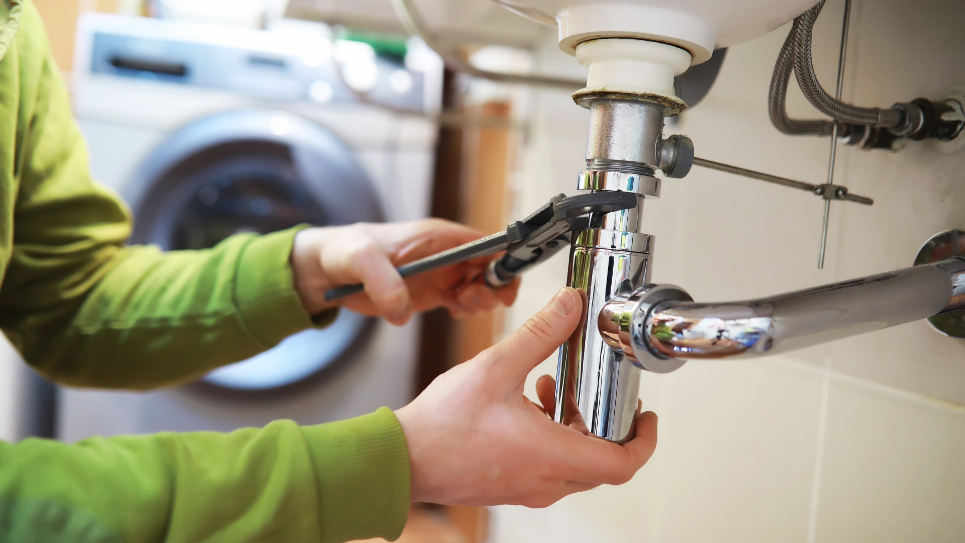 A person fixing a faucet in a bathroom