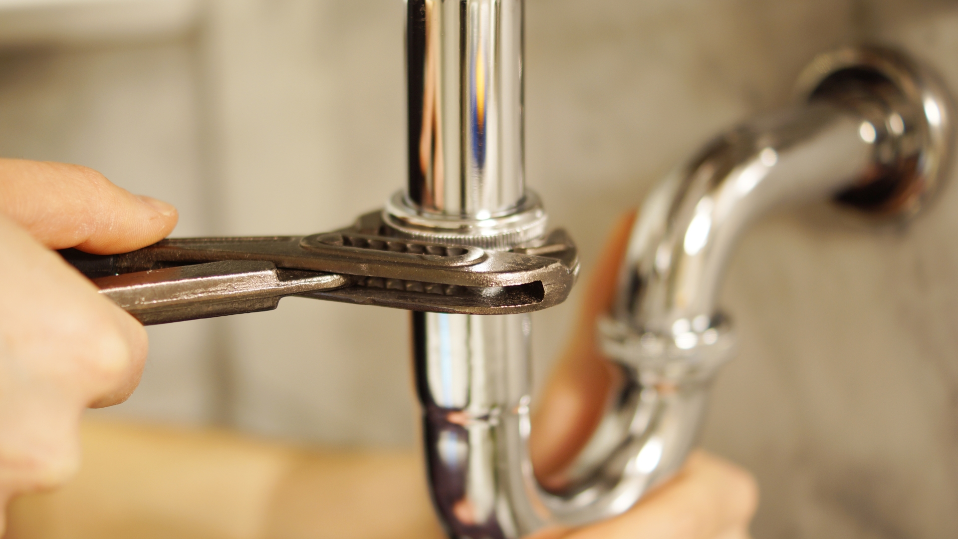 A person fixing a faucet with a wrench